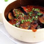 eggplant stew with tomatoes in a pale dish.