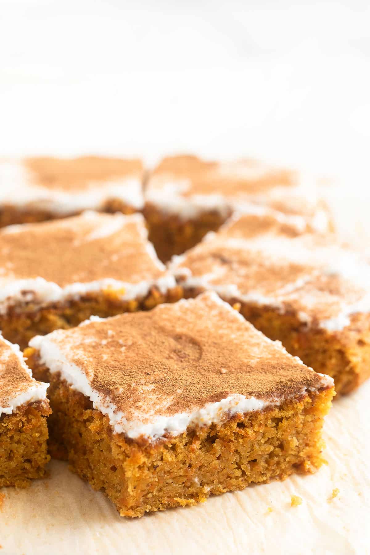 carrot cake squares with vegan coconut frosting, sprinkled with cinnamon.