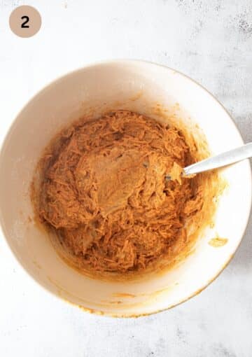carrot cake batter mixture stirred with a spoon in a bowl.