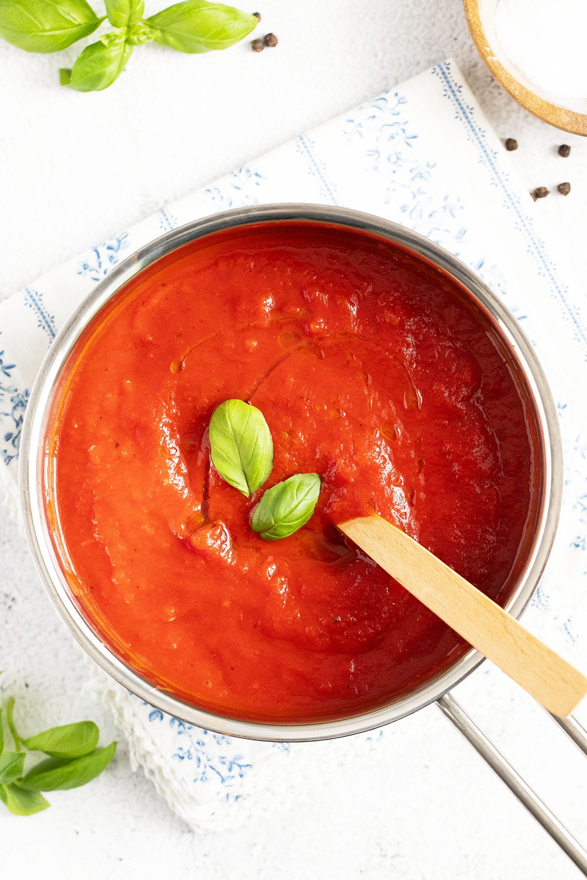 stirring marinara sauce with a wooden spoon in a saucepan.