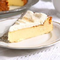 slice of creamy cake topped with whipped cream and sprinkled with sugar.