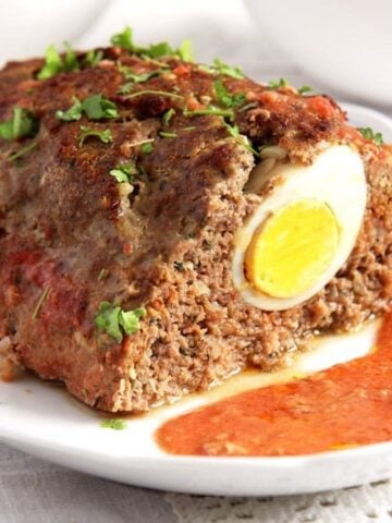 meatloaf with eggs served with tomato sauce on a platter.