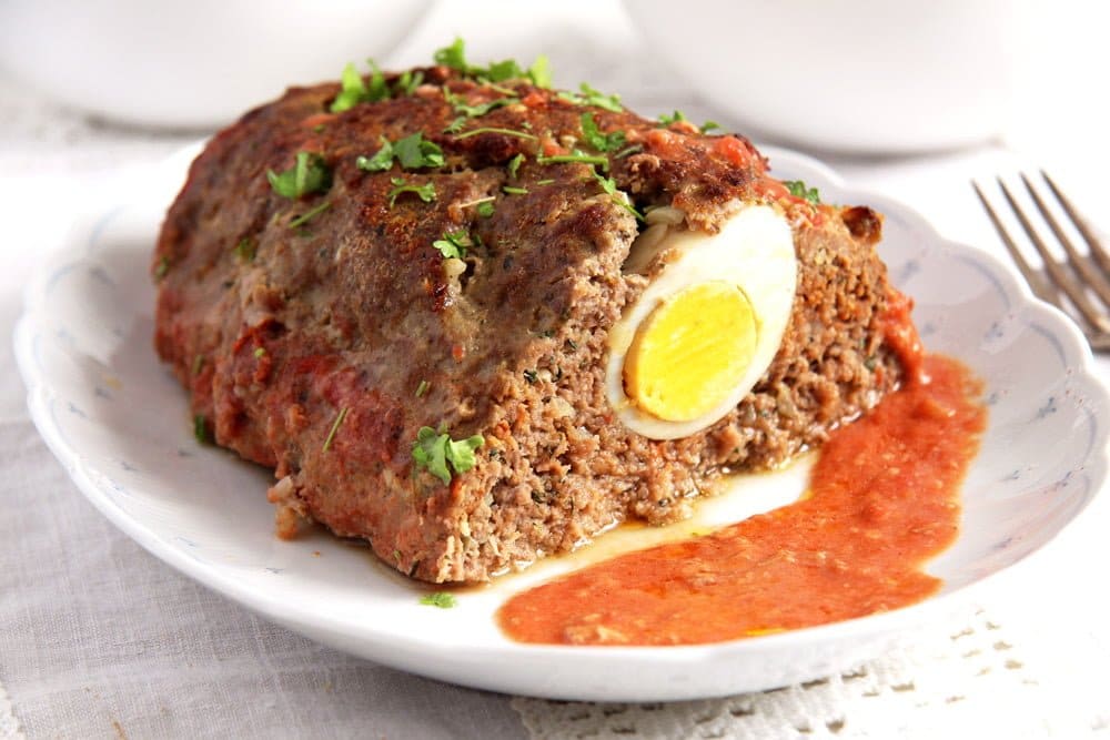 meatloaf with eggs served with tomato sauce on a platter.