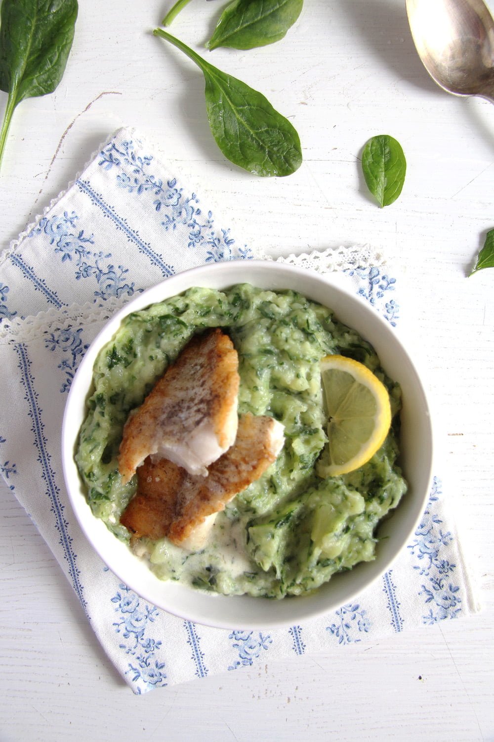 Spinach potato mash with fish and lemon in a bowl