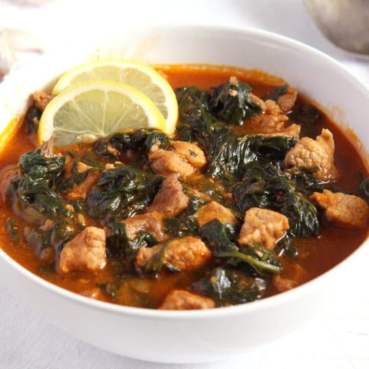 pork and spinach recipe with tomato sauce and lemon in a bowl