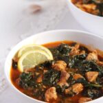 spinach stew with meat and tomatoes in a white bowl