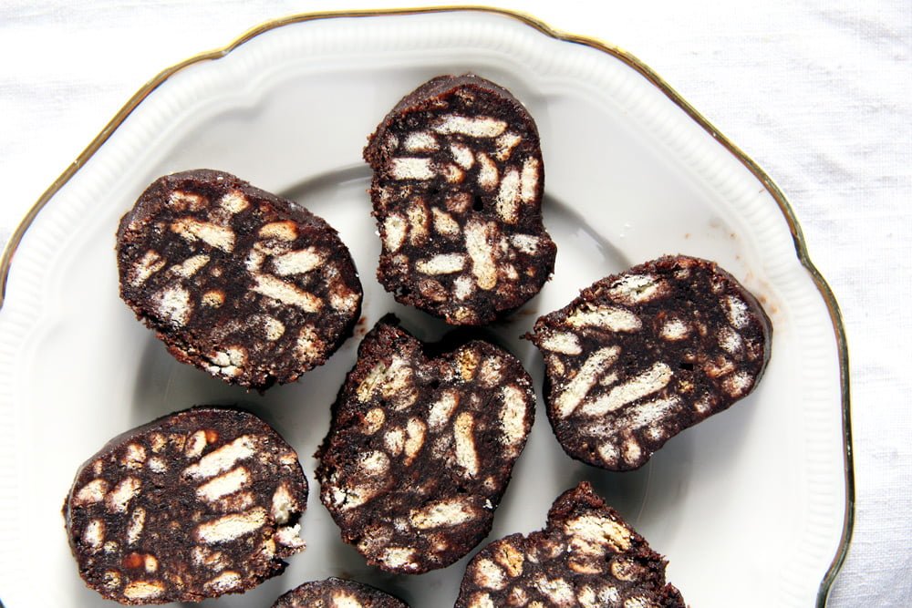 romanian chocolate salami with biscuits sliced on a plate.