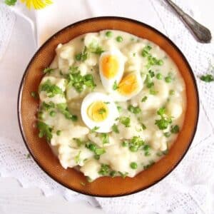 bowl with cauliflower with white sauce and boiled eggs on top.