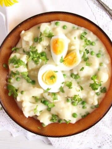 bowl with cauliflower with white sauce and boiled eggs on top.
