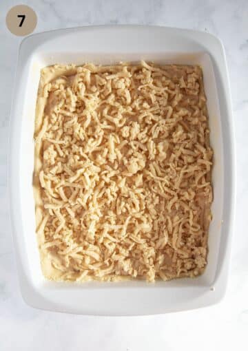 unbaked apricot cake with grated crumbles in a baking dish.