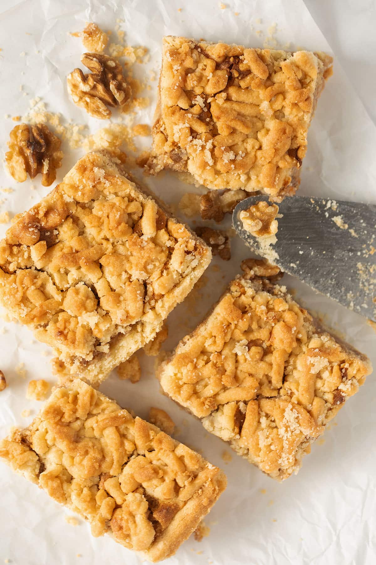 four pieces of apricot jam cake and walnuts on parchment paper.