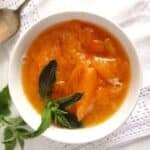 fresh apricot sauce garnished with mint leaves in a small bowl.