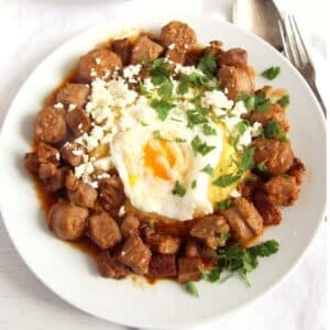 a plate with tochitura or moldavian sausage stew with a fried egg on top.