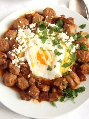 a plate with tochitura or moldavian sausage stew with a fried egg on top.