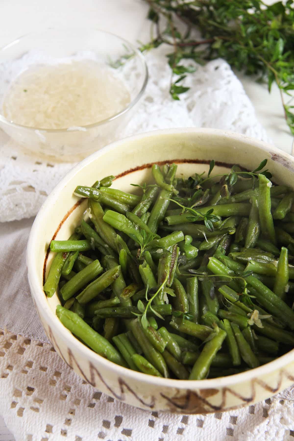 traditional romanian bowl full of garlicky green beans, more garlic sauce in a bowl behind it.
