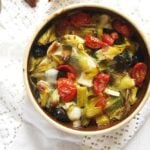 small clay pot with leeks, tomatoes and black olives