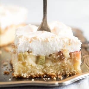 piece of rhubarb meringue cake with a fork sticking in it.