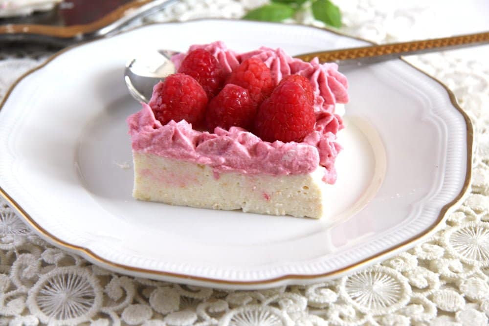 cheesecake with raspberries and sour cream sliced on a plate