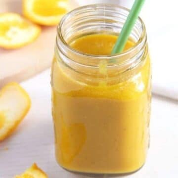 apple turmeric smoothie in a jar with a green straw in it.