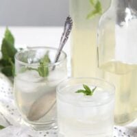 lemon mint drink in glasses and bottles of syrup behind