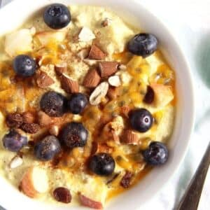 muesli with yogurt, blueberries, almonds, apples and cinnamon in a bowl.