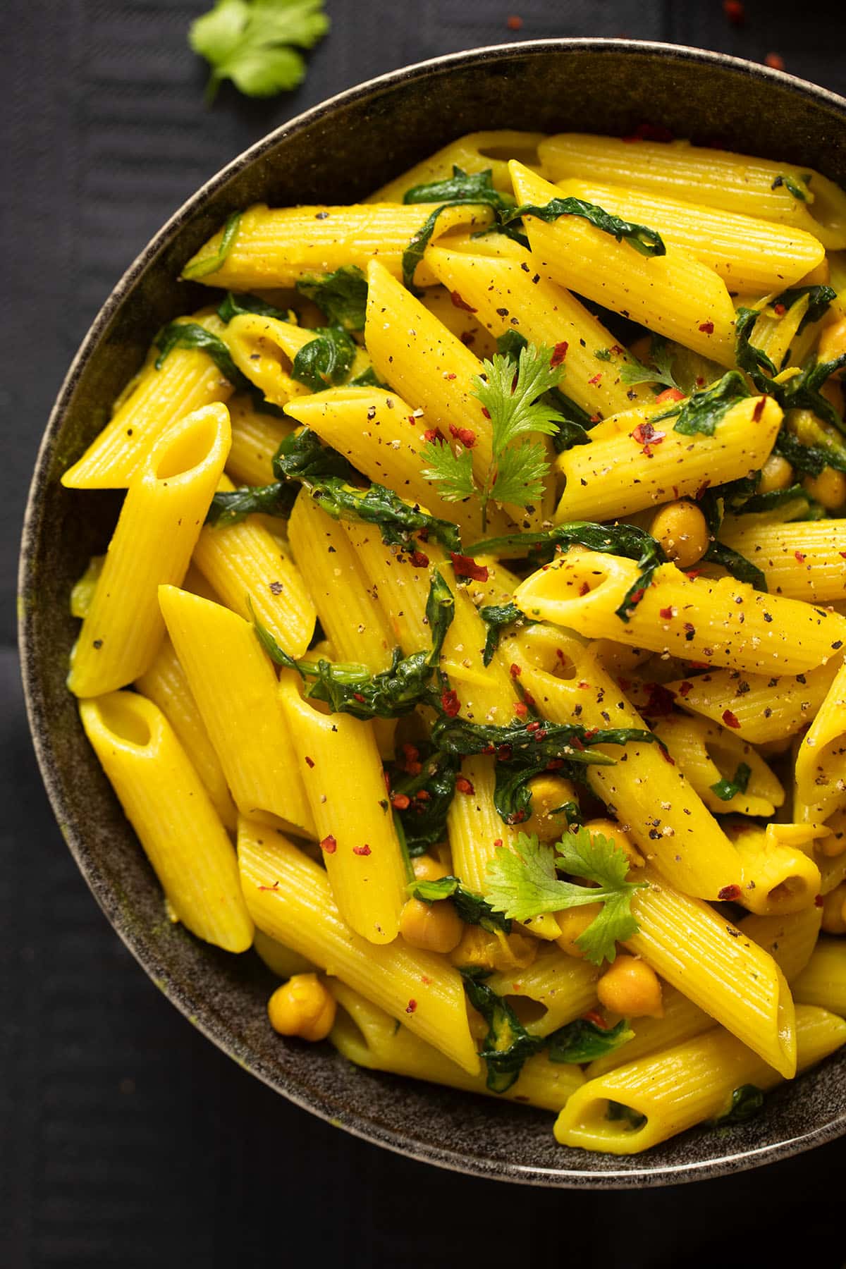 penne with turmeric sauce with chickpeas and spinach in a bowl.