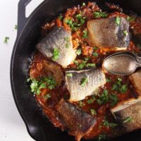 trout stew with tomatoes being served from the pan