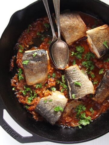 stewed trout with tomatoes in a skillet served with polenta in a bowl