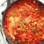 white fish in tomato sauce and sprinkled with parsley in a large skillet.
