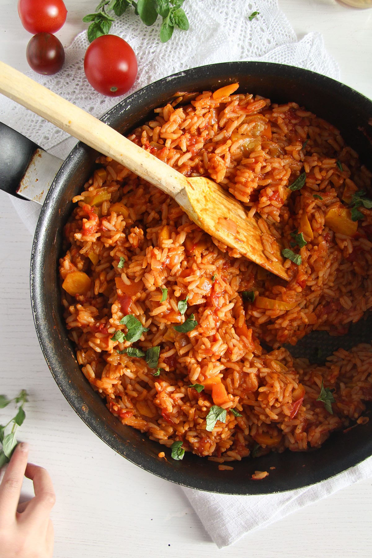 stirring tomato rice with zucchini with a wooden spoon.