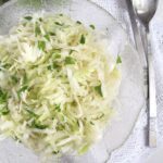 bowl with white cabbage, serving salad spoons and parsley.