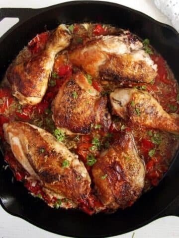 golden brown chicken pieces in a pepper and garlic sauce in a skillet.