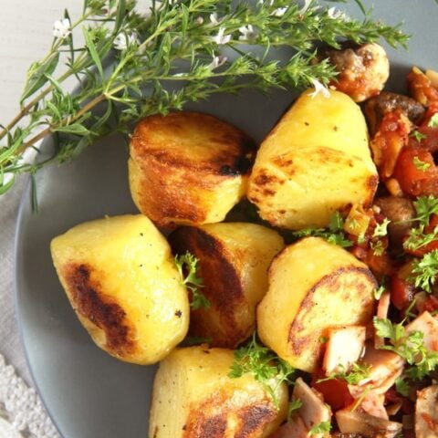 fried gypsy potatoes with bacon on a gray plate with thyme