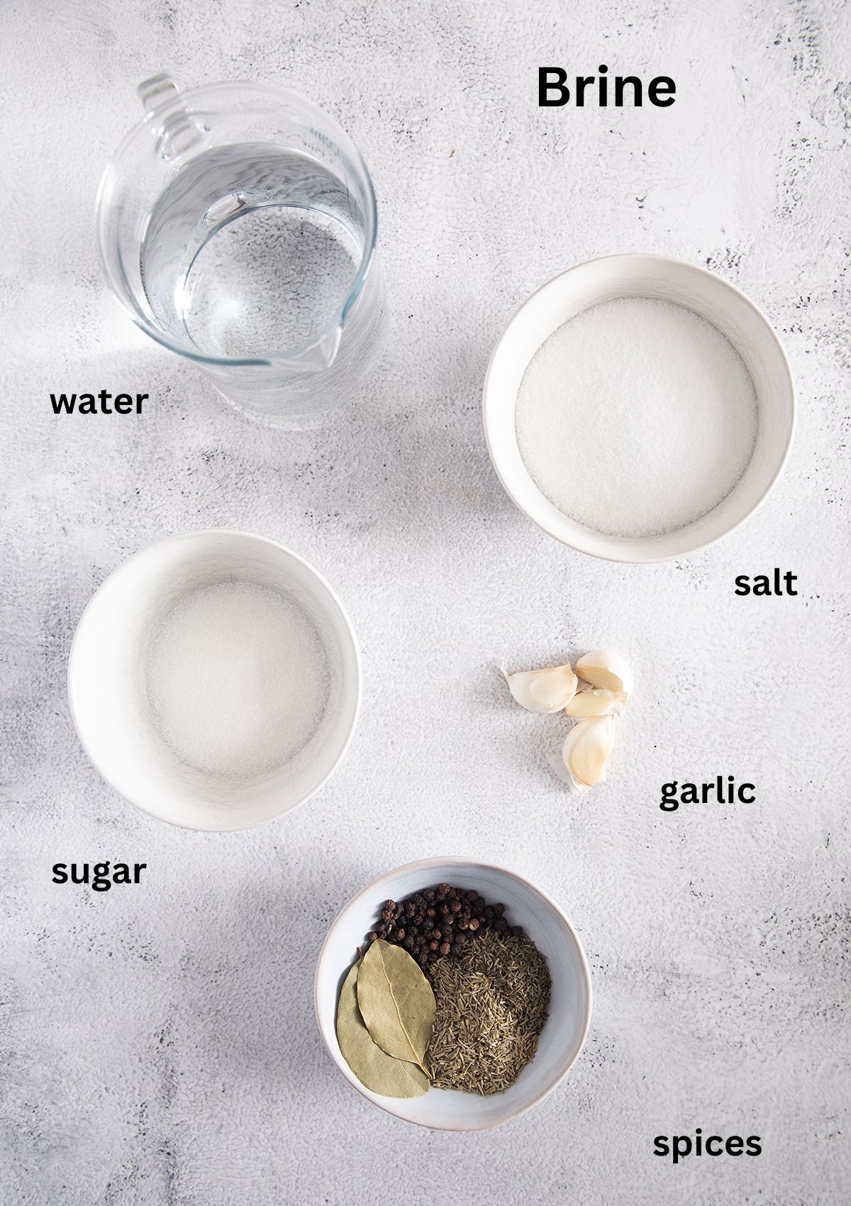water, salt,sugar, spices and garlic for making brine in bowls on the table.