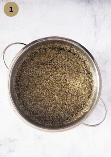a pot containing turkey brine with lots of dried herbs in it.