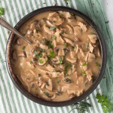 turkey fricassee with mushrooms and sauce in a bowl with a spoon in it.