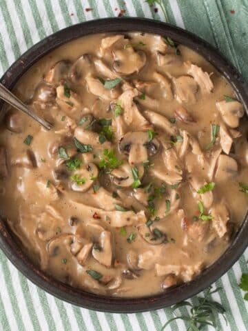 turkey fricassee with mushrooms and sauce in a bowl with a spoon in it.