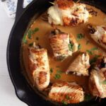 turkey roulades with wine sauce in a skillet.
