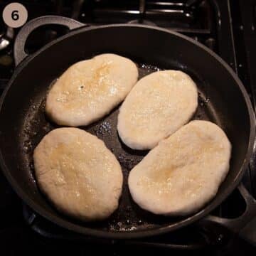 four small naan breads cooking in a pan.