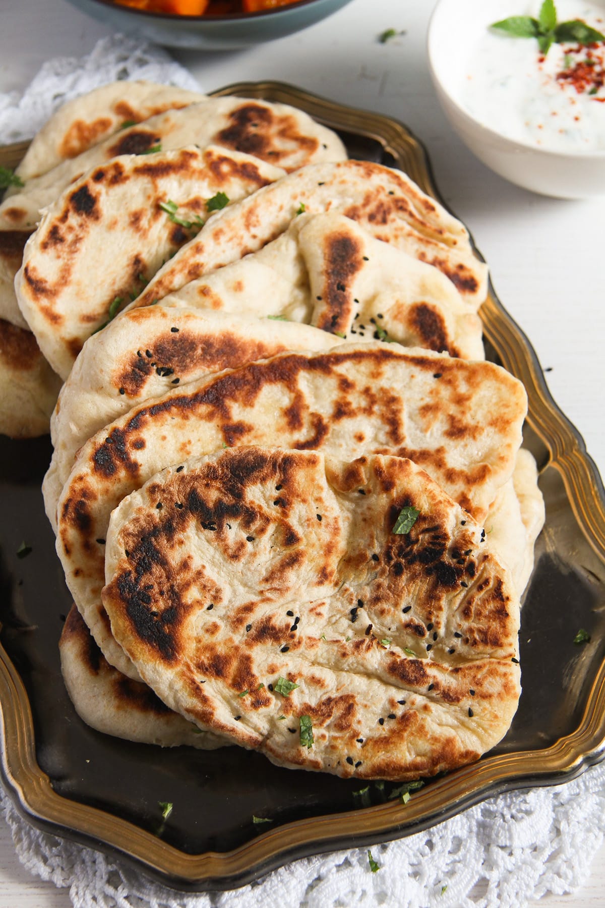 afghan naan bread pieces on a platter and bowl of dip behind.