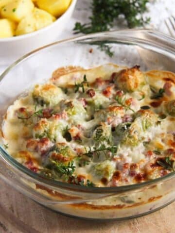 brussel sprouts cream cheese casserole with golden cheese on top in a small dish.
