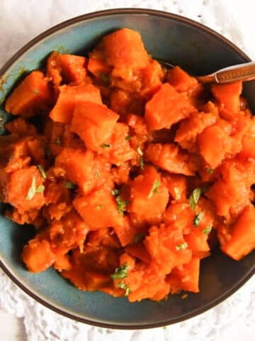afghan braised pumpkin cubes in a blue bowl with a fork in it.