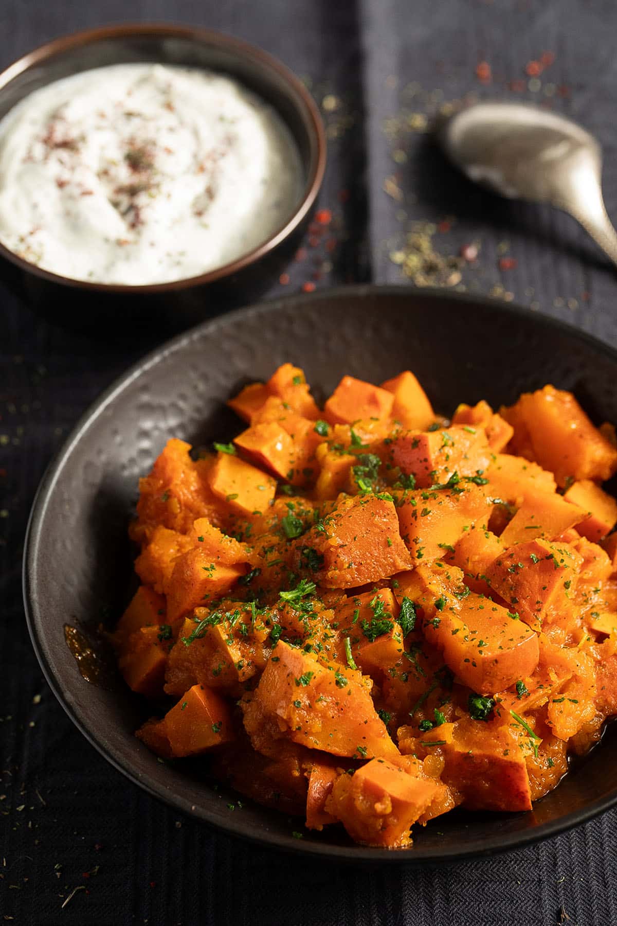 a bowl with braised pumpkin and a small with yogurt mint dip.