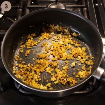 stirring lots of spices into cooking onions in a pan.