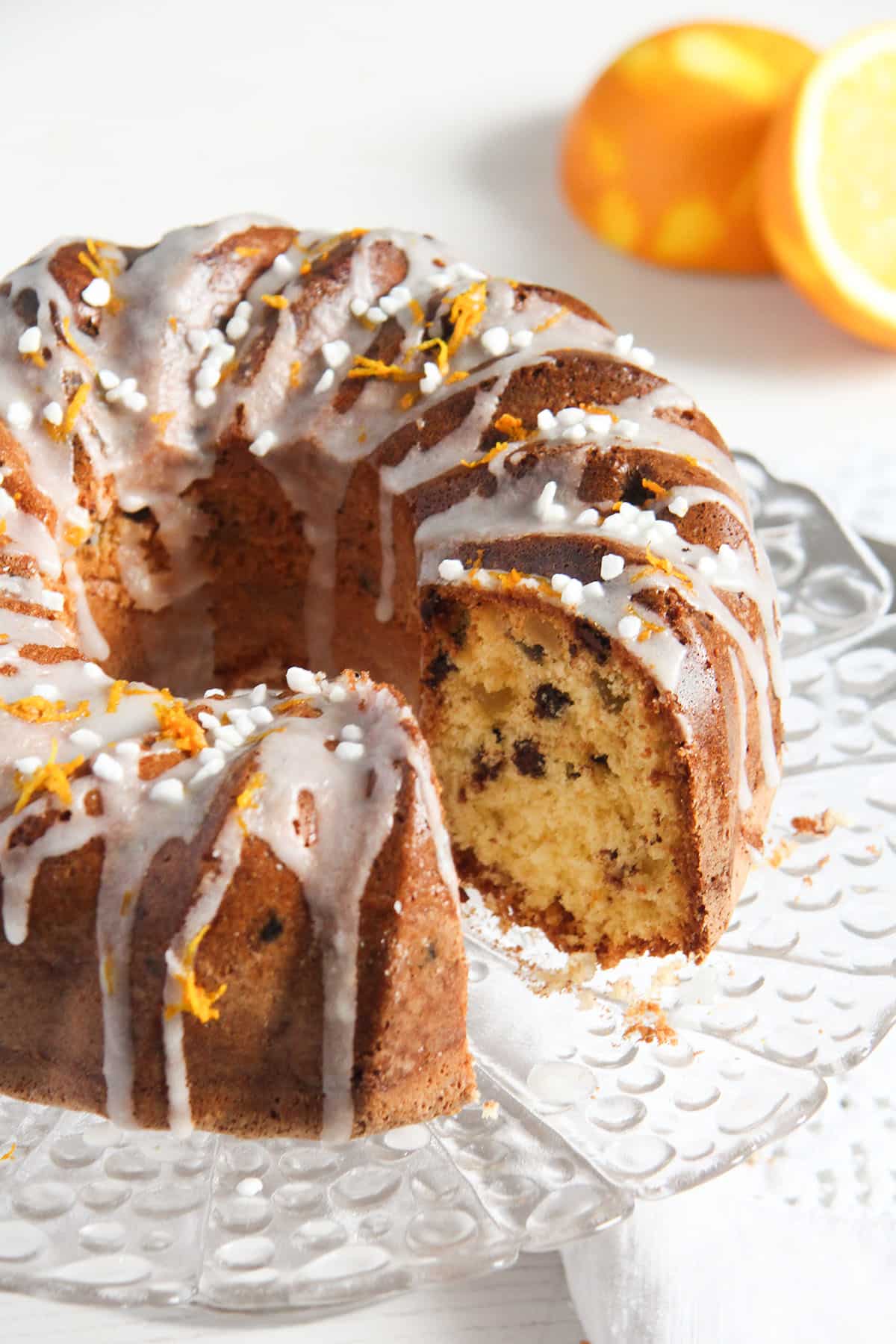 orange raisin cake with a slice cut off to show the crumb and a halved orange behind it.