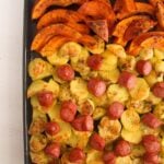 slices of pumpkin, potatoes and sausages arranged on a baking tray.