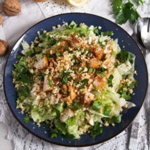 celeriac pear salad with walnuts and cheese on a blue plate.