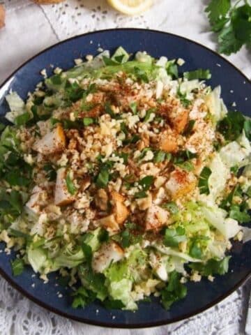 celeriac pear salad with walnuts and cheese on a blue plate.