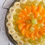 vanilla pudding tart covered with bananas, mandarins and grapes