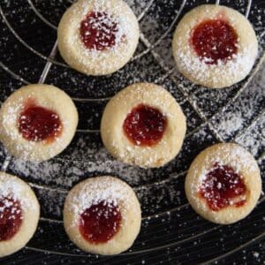 german thumbprint cookies filled with jam on a wire rack.